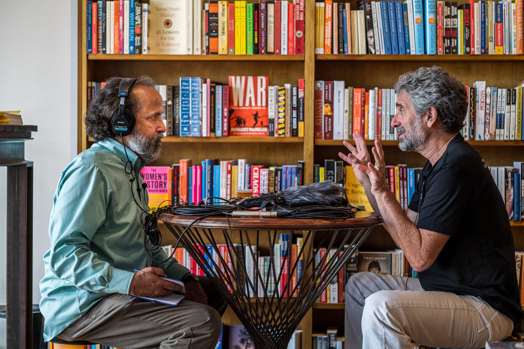 A documentary interview being recorded against a wall of books — the kind of footage that fills an archive